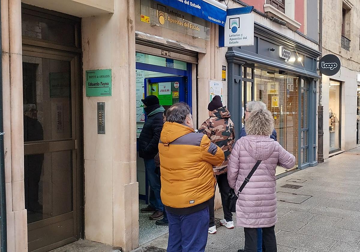 Un grupo de personas hace cola frente a una administración de lotería.