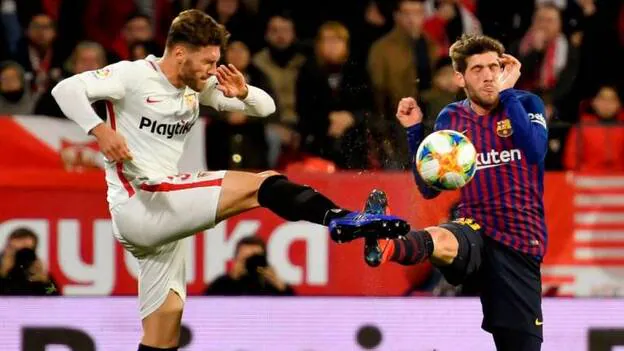 El defensa del Sevilla Sergi Gómez (i) pelea un balón con Sergi Roberto, del FC Barcelona, durante el partido de ida de los cuartos de final de la Copa del Rey que disputan esta noche en el estadio Sánchez Pizjuán, en Sevilla. / Efe.