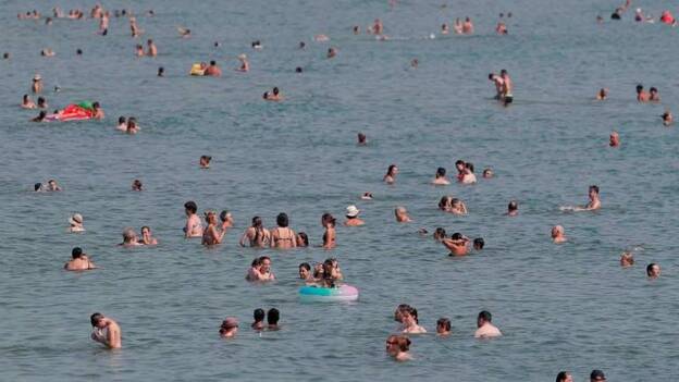 Un gran número de personas se sumergen en la playa de la Malvarrosa (Valencia) ante las altas temperaturas de este jueves. / Efe
