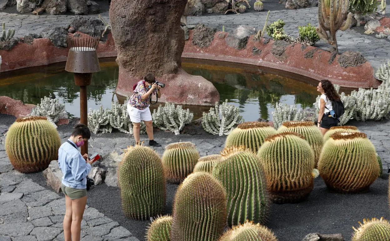 Arriba, un trabajador turístico en Gando; José María Mañaricua y Jorge Marichal. Debajo, imagen de turistas en el Jardín de Cactus de Tahíche, en Lanzarote. 
