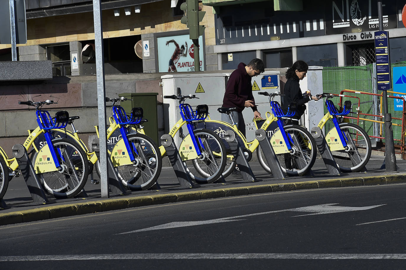Dos personas cogen bicicletas. 