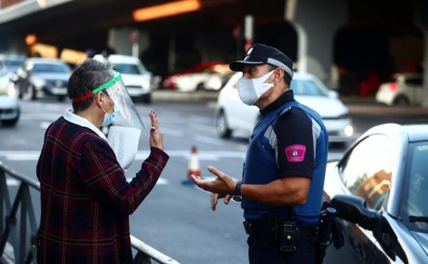 Un policía local habla con una mujer en Vallecas