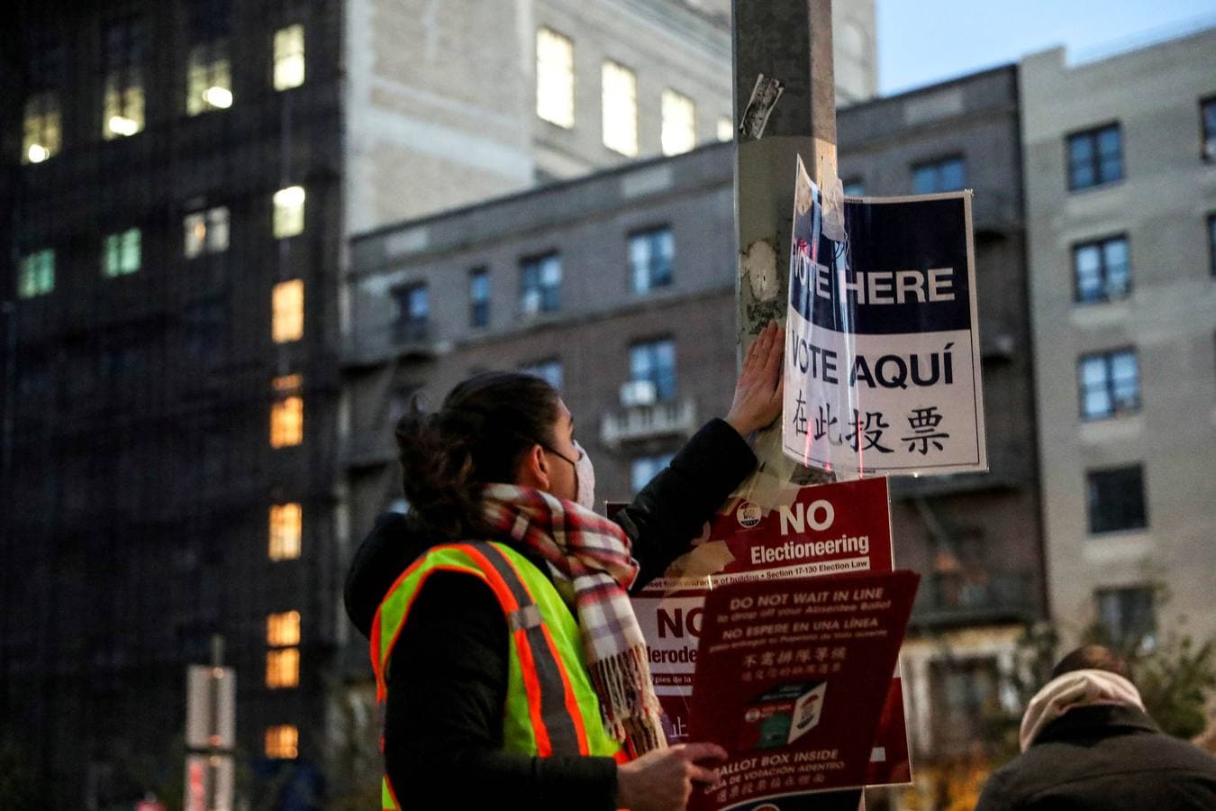 Un trabajador coloca carteles para los votantes antes de que se abran las urnas frente a la Biblioteca Pública de Brooklyn en Nueva York.