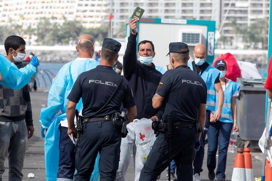 Un inmigrante muestra un pasaporte marroquí en un intento de salir del muelle de Arguineguín. 