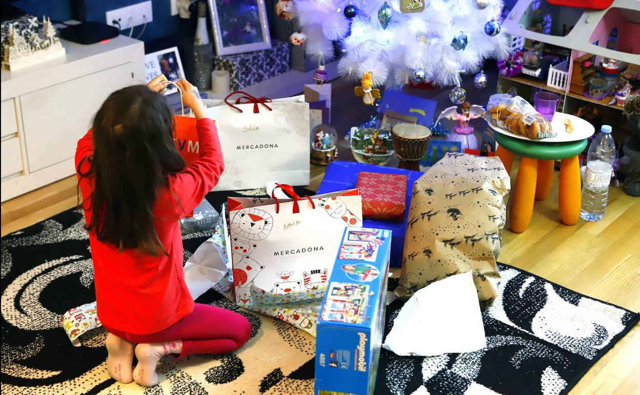 Una niña abre los regalos de Reyes.