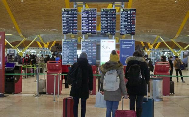 Tres personas observan los paneles de vuelos ayer en Barajas. 