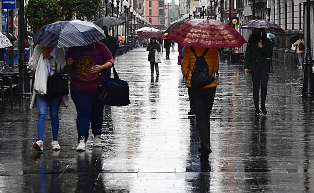Paseantes este viernes por una empapada calle Triana, en la capital.