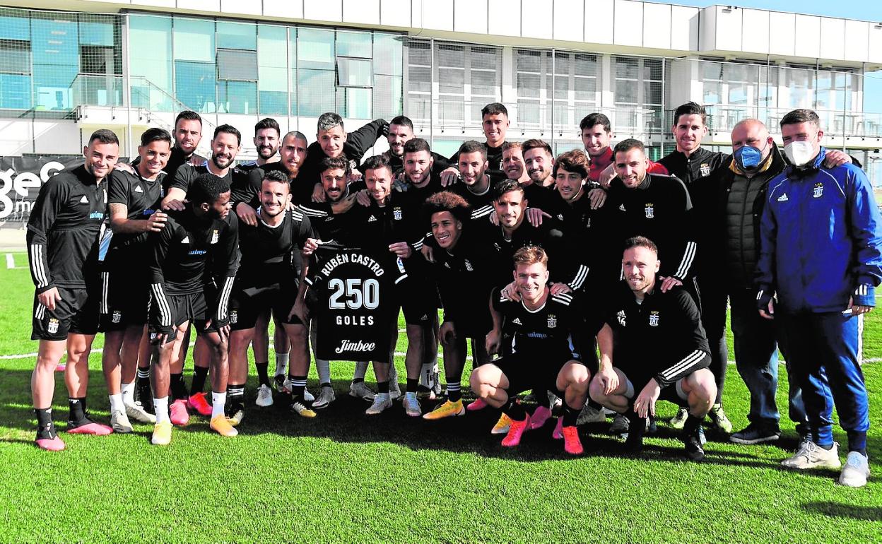 Rubén Castro sostiene una camiseta conmemorativa de sus 250 goles entre Primera y Segunda División, rodeado de sus compañeros de equipo. 