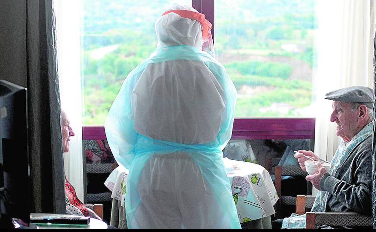 Una trabajadora de la residencia San Carlos de Celanova (Ourense) sirve el desayuno a unos ancianos. 