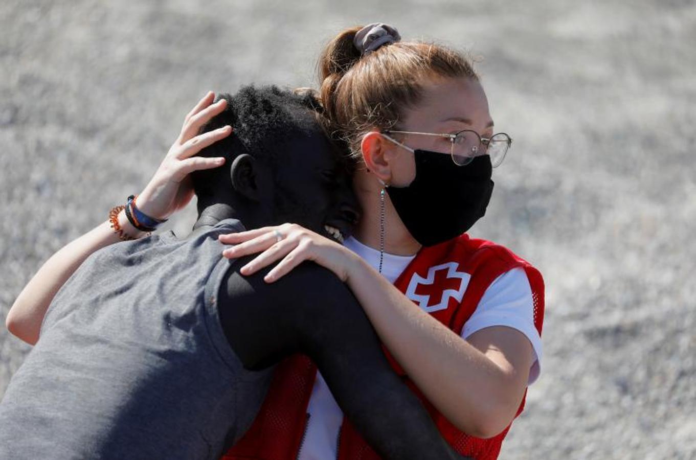 Una voluntaria de la Cruz Roja abraza a un inmigrante en la playa de El Tarajal.