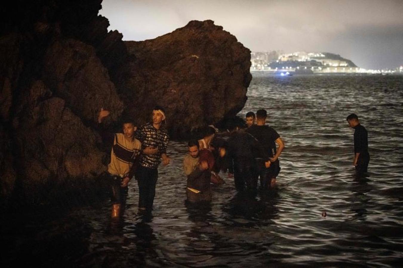 Los migrantes marroquíes caminan hacia aguas poco profundas en la ciudad norteña de Fnideq mientras intentan cruzar la frontera de Marruecos al enclave español de Ceuta.