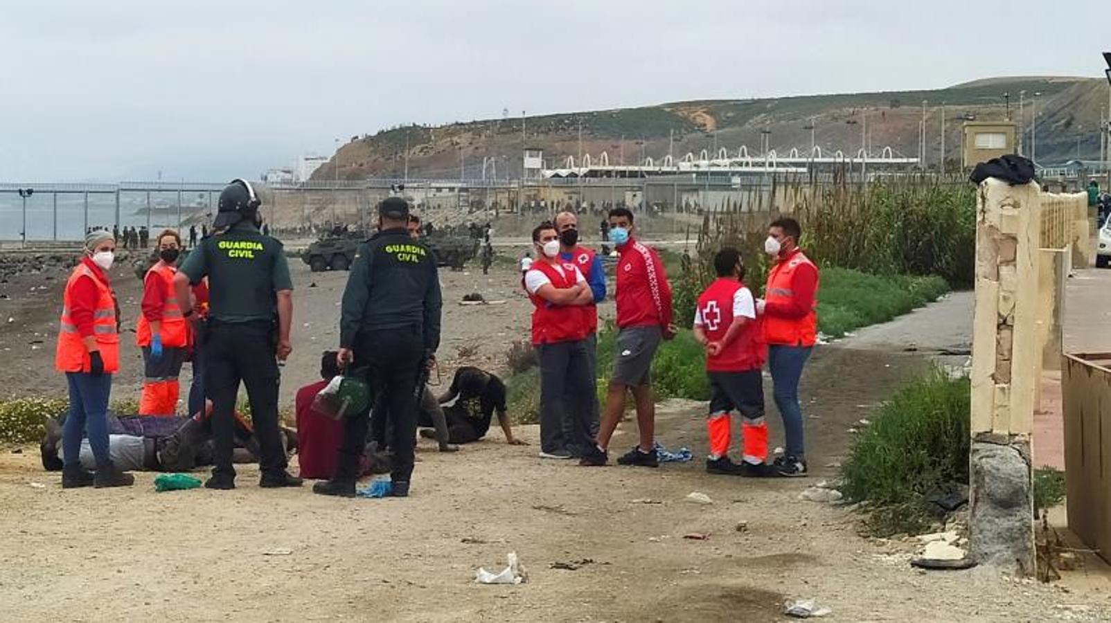 Miembros de la Guardia Civil y de la Cruz Roja atienden a un grupo de inmigrantes marroquí en uno de los espigones fronterizos de Ceuta.
