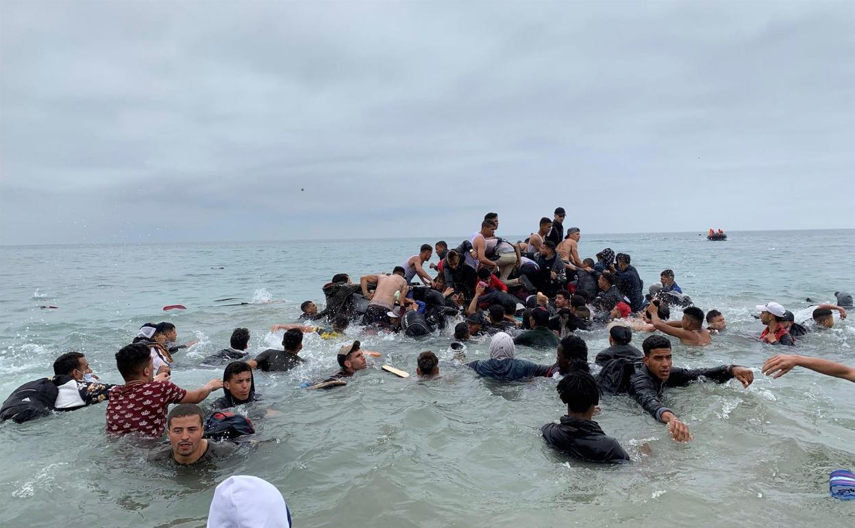 Un grupo de personas se hacen con una embarcación de las autoridades marroquíes en la playa de Fnideq (Castillejos) para cruzar a Ceuta. 