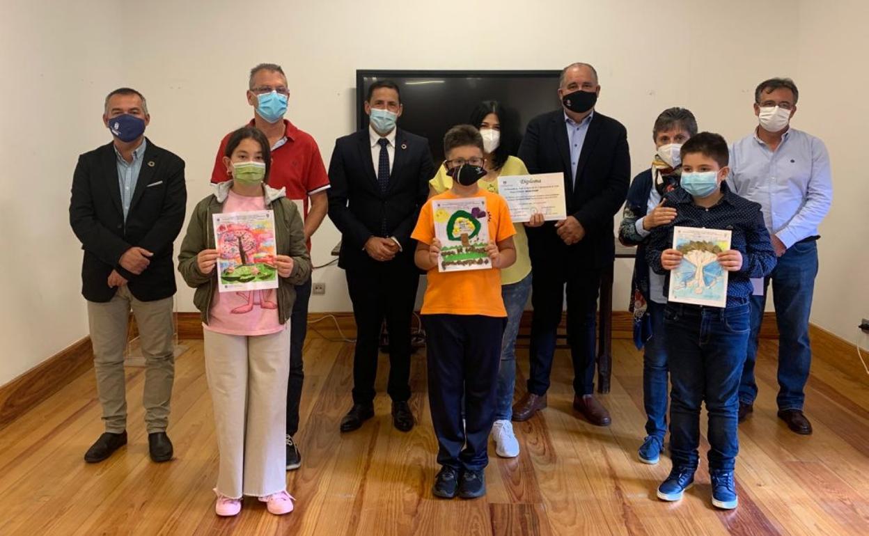 Los tres finalistas del concurso medioambiental posan con sus obras junto a las autoridades políticas. 