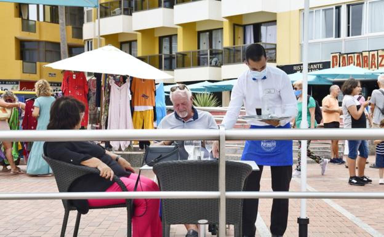 Un camarero atiende una mesa de terraza en el Paseo de Las Canteras. 