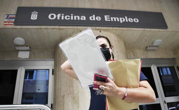 Una ciudadana sale de una oficina de empleo con los documentos en la mano. 