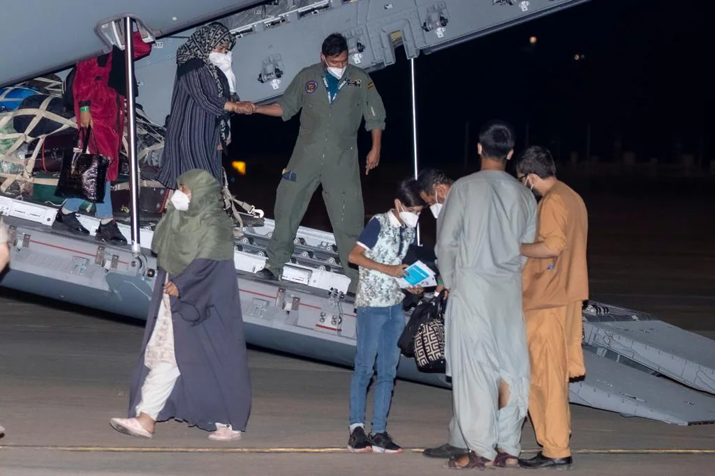 Un militar español ayuda a descender del avión a una mujer afgana. 