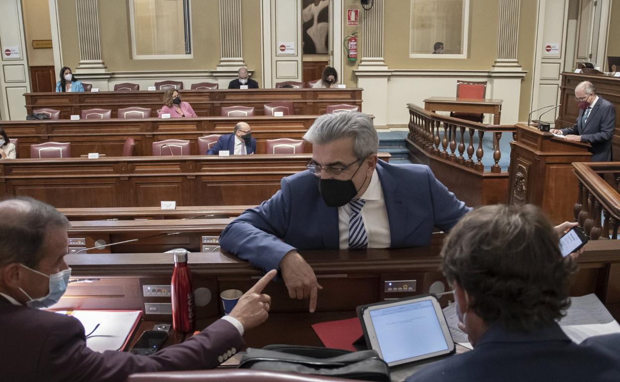 Imagen de archivo del vicepresidente y consejero de Hacienda del Gobierno de Canarias, Román Rodríguez (c), hablando con dos diputados socialistas en el Parlamento regional. 