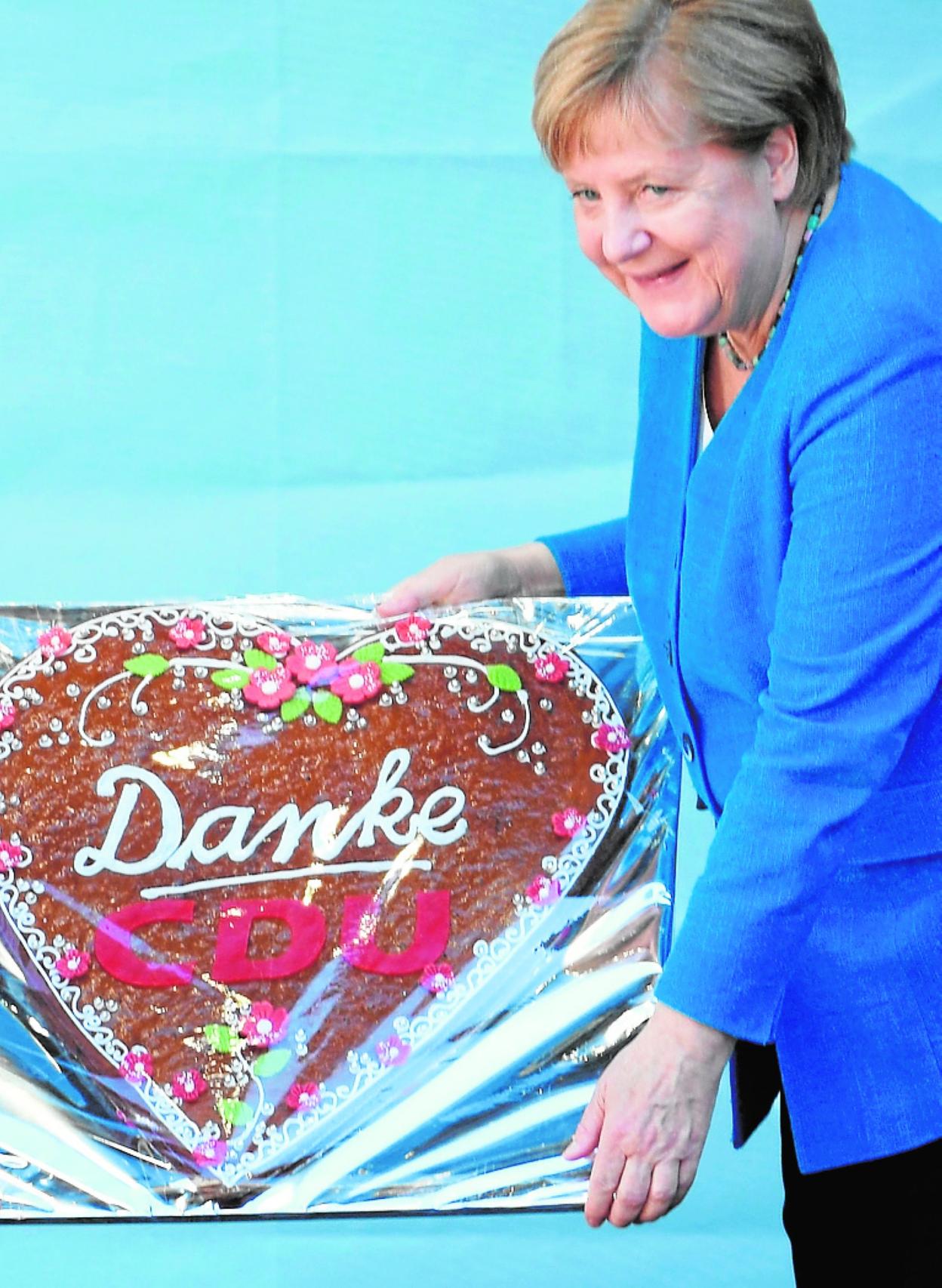 Merkel, con una tarta de agradecimiento de su partido. 