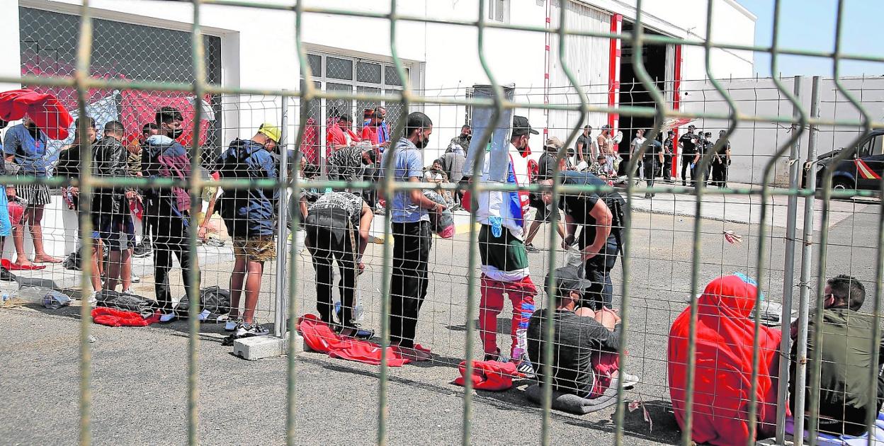 Grupos de inmigrantes junto a agentes de la Policía Nacional ayer en Lanzarote. Arriba, a la izquierda, el momento en que llegan más baños químicos. 