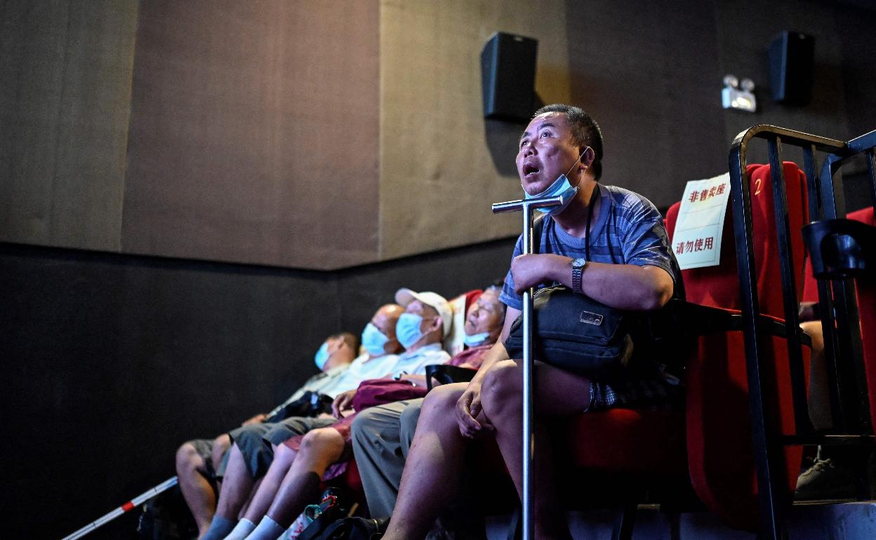 Wang lee una película en el cineclub mientras Zhang y otros cinéfilos ciegos siguen sus explicaciones 