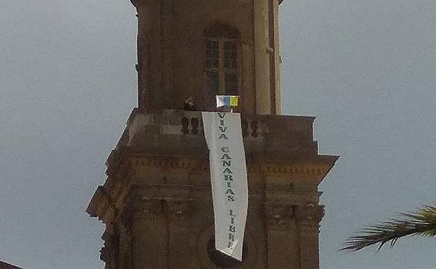 Foto captada del momento en que los activistas desplegaron este jueves la pancarta en la torre sur de la Catedral. 