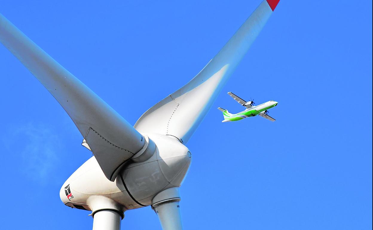 Entre las aspas del molino eólico de Informaciones Canarias SA, editora de CANARIAS7, en Arinaga, un avión de Binter. 