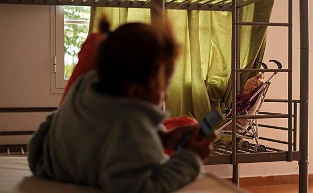 En la imagen, una niña que llegó sola en patera a Canarias mira el teléfono móvil.
