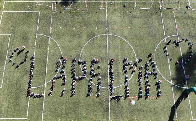 Imagen principal - Arriba, imagen tomada con un dron del nombre de La Palma formado por el alumnado del colegio. Abajo, los juguetes recaudados y el edil Juan Francisco Artiles, en el momento en que se dirige a los chiquillos. 