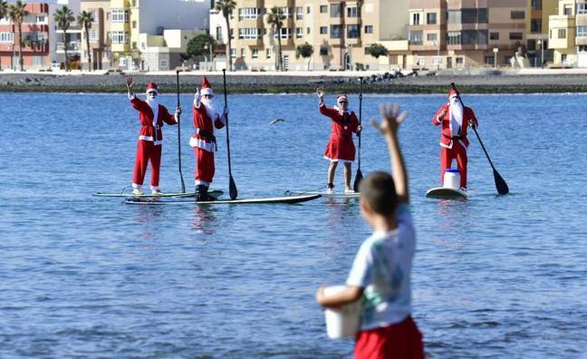 El día de Navidad tiene múltiples expresiones festivas y Papá Noel es unos de sus protagonistas. Antes de entregar los regalos esta noche, Papá Noel y sus ayudantes se dieron un chapuzón tras llegar a la corta de Arinaga haciendo paddle surf este viernes.