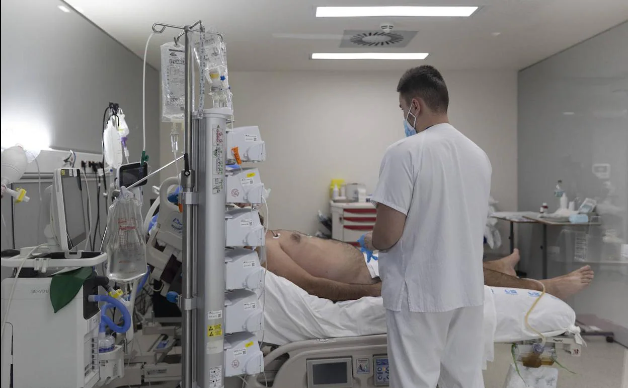 Un sanitario atiende a un paciente ingresado en la UCI del Hospital Isabel Zendal de Madrid.