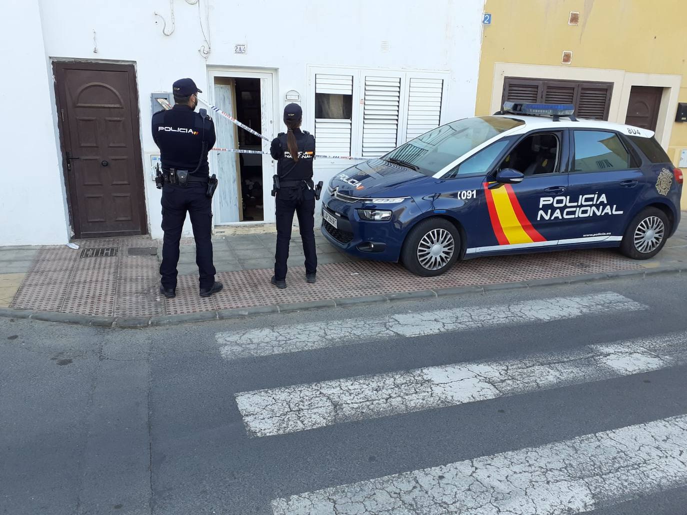 Agentes de la Policía Nacional, en el portal de la vivienda donde se registró la muerte. 
