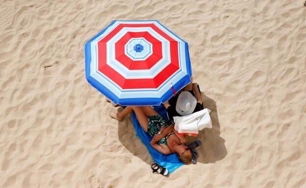Dos turistas toman el sol en las playas del Mediterráneo.