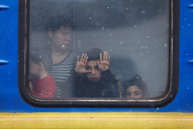 Un grupo de niños ucranianos se despiden de sus familiares desde la ventana de un tren que sale desde Lviv con destino a Polonia. 
