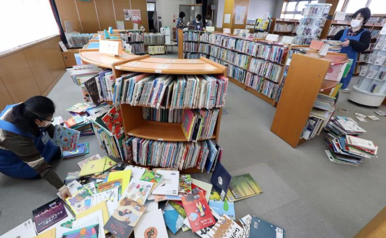 Los miembros del personal recogen libros caídos en una biblioteca en Koriyama, Fukushima.