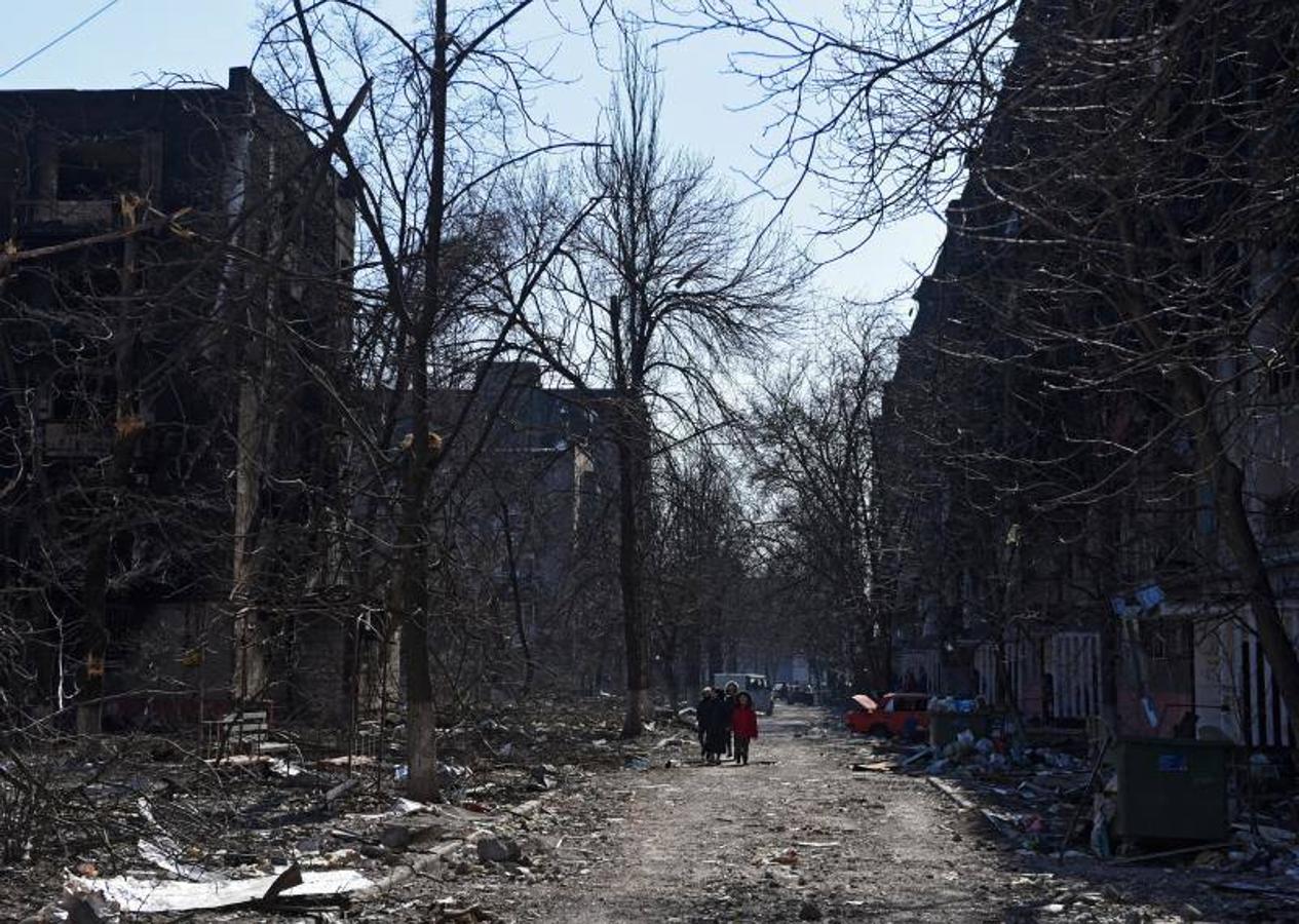 Personas caminan entre escombros y al lado de edificios destruidos por los bombardeos en Mariúpol.