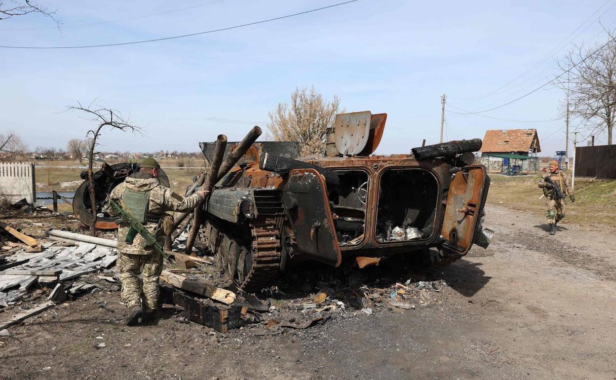 Un soldado ucaniano examina los restos de un blindado ruso, destruido al norte de Kiev.