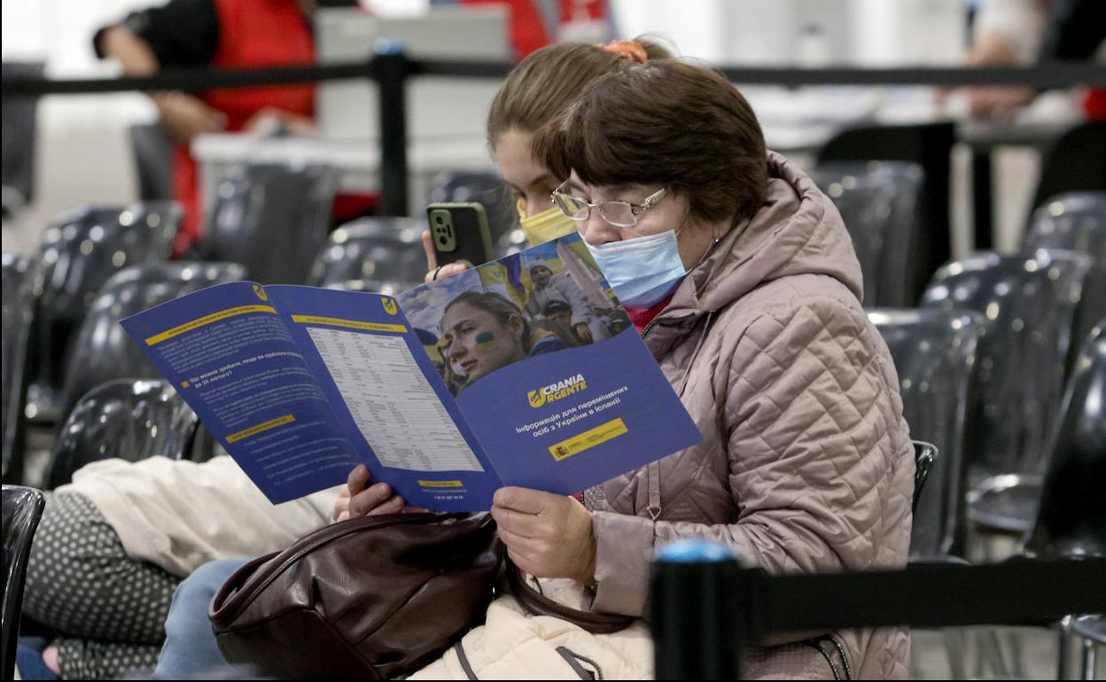 Varias personas esperan ser atendidas en el centro de refugiados habilitado en Fira de Barcelona. 