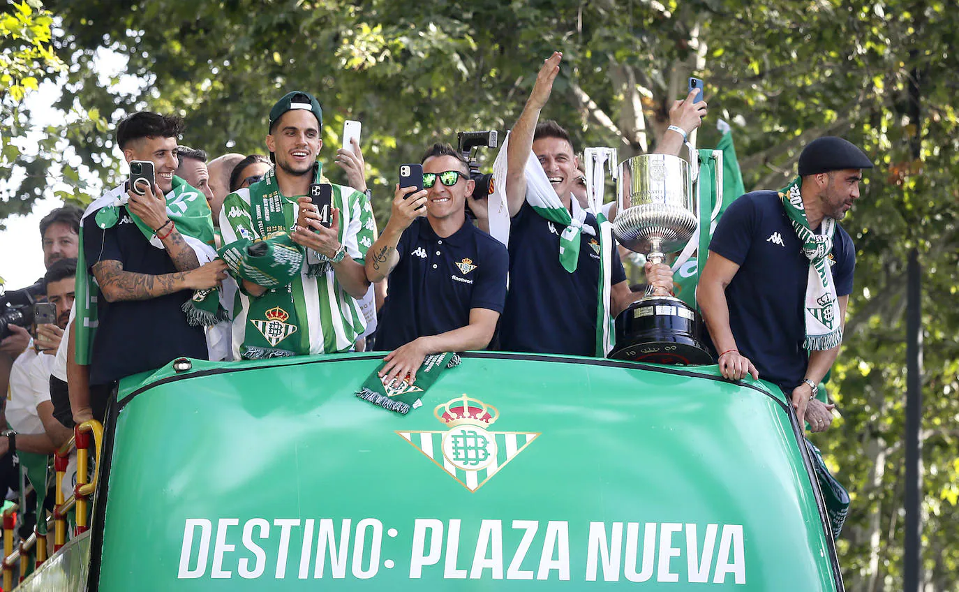 Jugadores del Betis saludan desde el autocar durante su recorrido con destino al ayuntamiento de Sevilla, para celebrar su título de Copa del Rey.