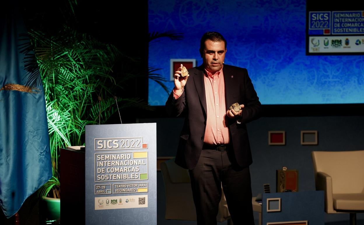En la imagen, Jorge Méndez muestra durante su ponencia dos tipos de rocas que contienen tierras raras. 