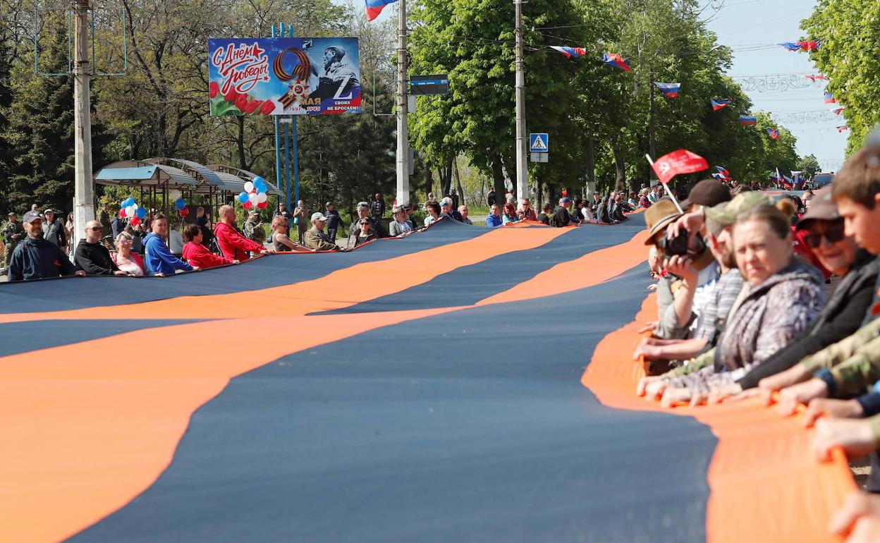 Prorrusos celebran el día de la Victoría en la ciudad de Mariupol con una bandera con los colores de San Jorge. 