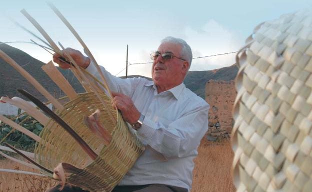 Ravelo González, en su casa de Vega de Río Palmas haciendo una cesta de caña. 