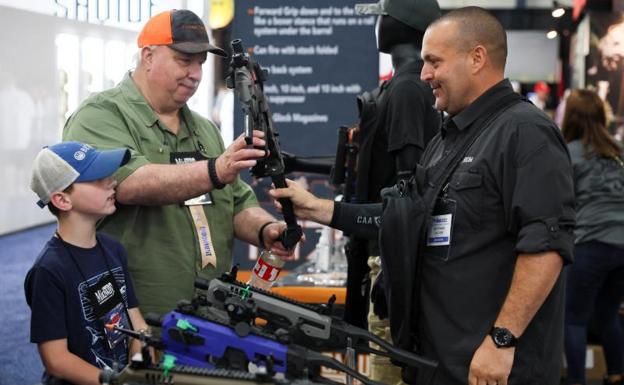 Un hombre sostiene un kit de conversión de pistola junto a un niño durante la convención que arrancó este viernes.