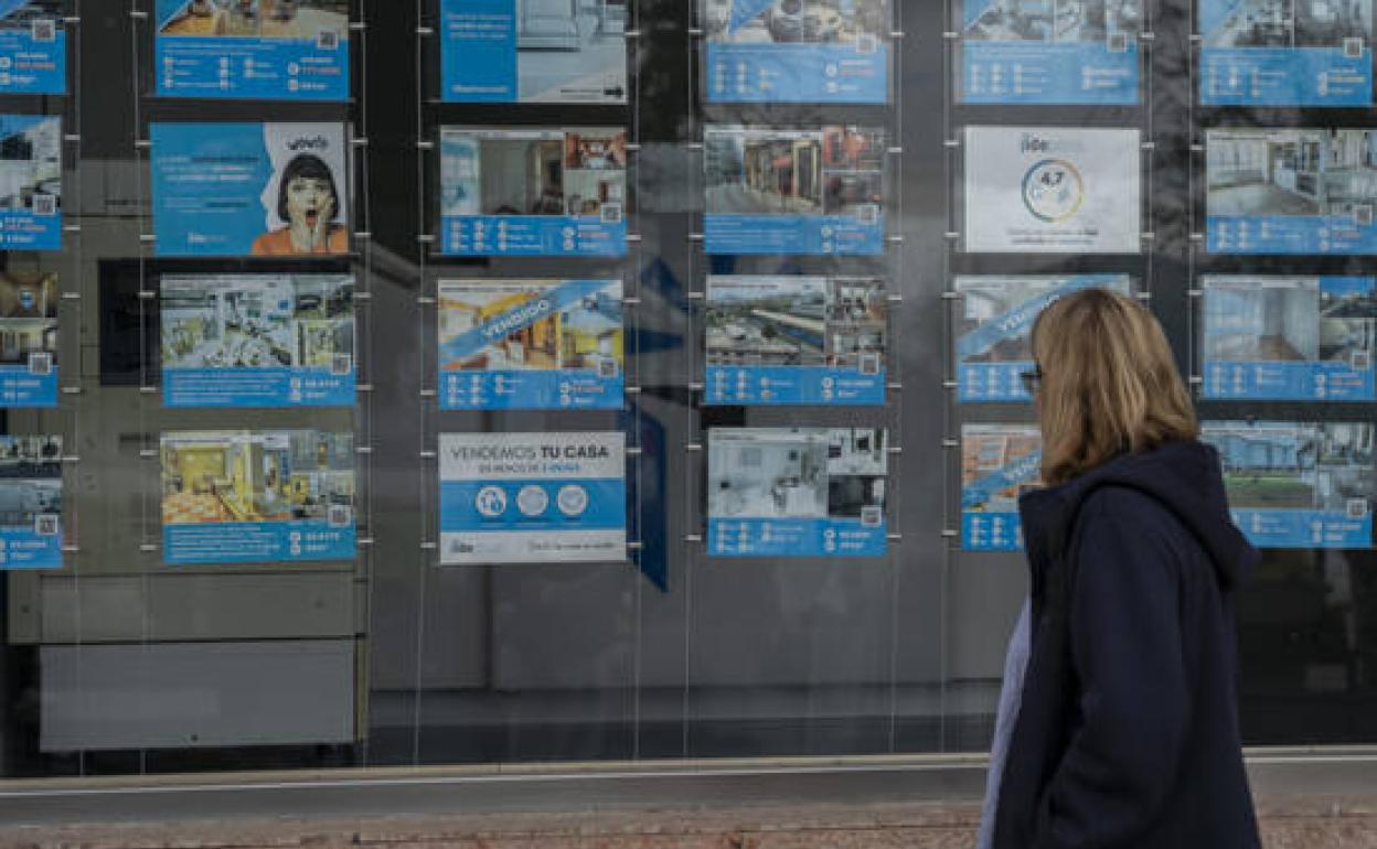Una ciudadana observa un cartel de venta de viviendas. 