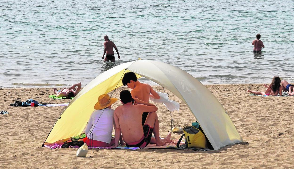 Una familia refugiándose del sol en la playa de Las Canteras. 