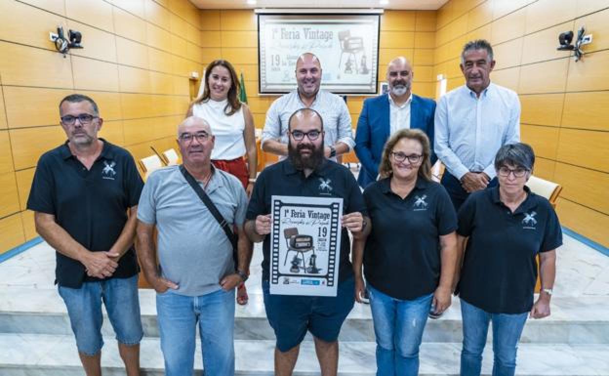 Vecinos y miembros del Cabildo, con el cartel de la feria. 