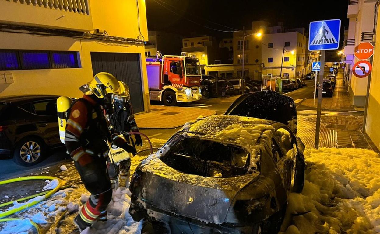 Bomberos sofocando las llamas en un vehículo. 
