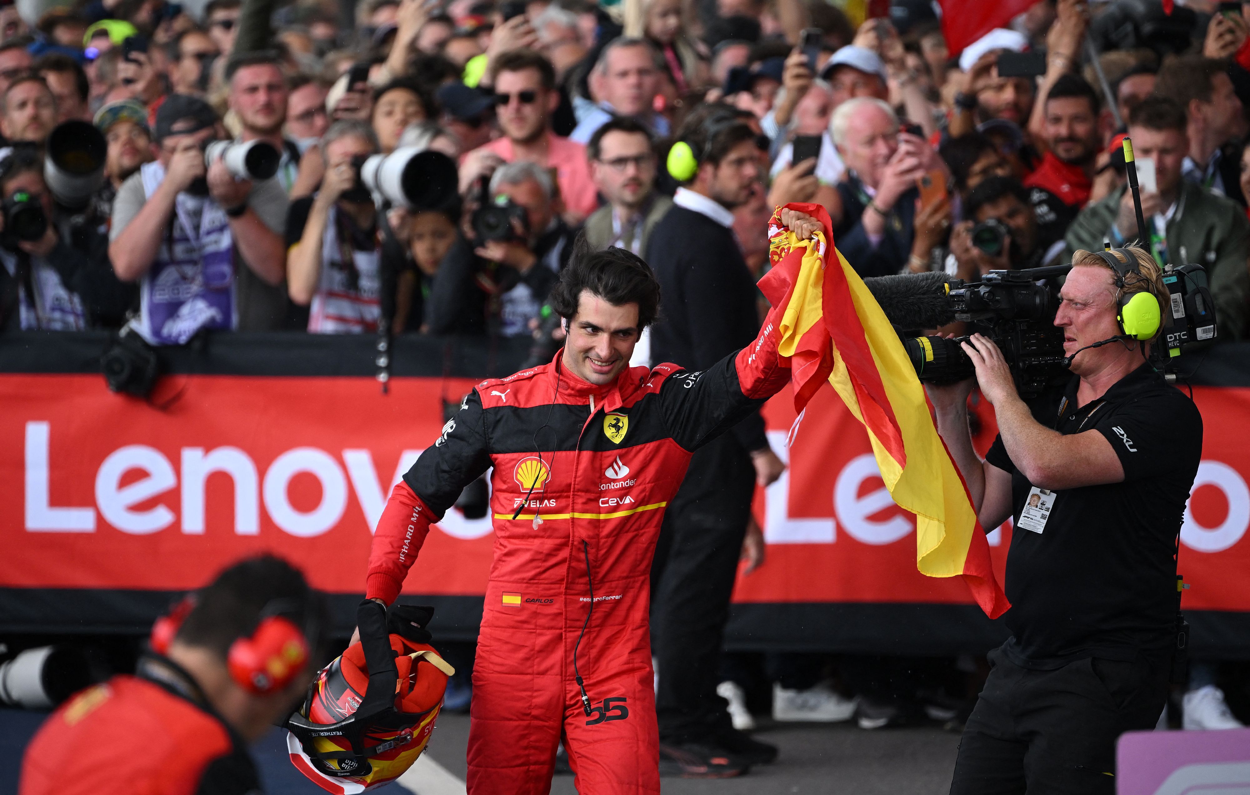 Carlos Sainz levanta el puño de su mano izquierda en la que lleva la bandera española.