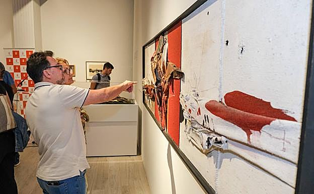 Dos asistentes a la muestra, ante una de las piezas exhibidas. 