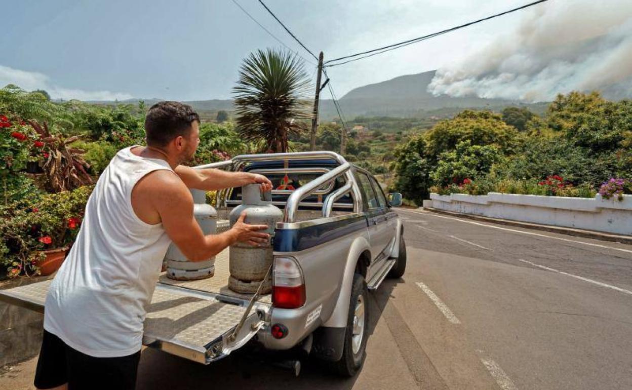 Un hombre carga bombonas de butano en su vehículo antes de abandonar la zona del incendio. 